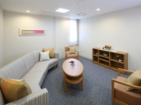 壁は白色、床にはグレーのカーペットが敷かれている。室内にある細長い窓からは陽の光が入る。天井には照明がいくつも設置されている。