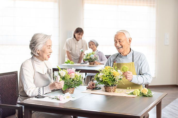 鉢植えの手入れをしている利用者様と、それを見守るスタッフ
