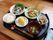 ごはんやおかずの他にデザートもついている。料理の横には、黒いトレーに乗せたおしぼりの準備がされている。