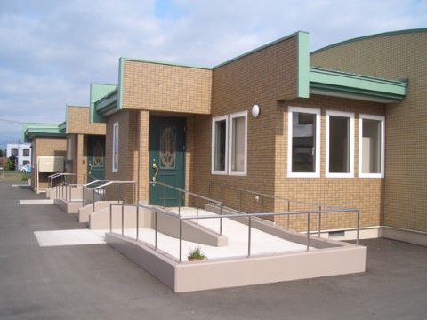 平屋建ての施設。玄関まではスロープができており、バリアフリー対応となっている。中から見えるよう窓も数個ついていて、防犯面でも役立つ。