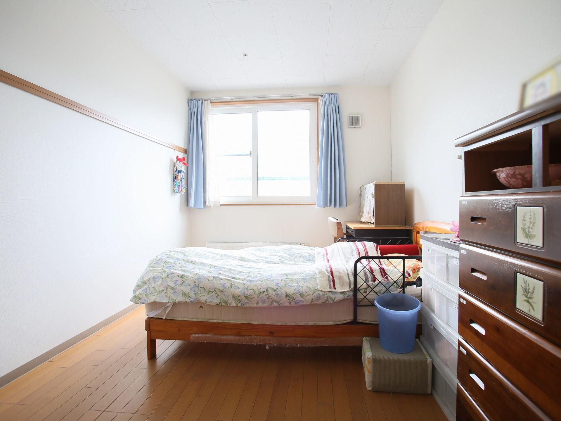 居室の窓からは明るい日の光がたっぷり差し込んでいる。室内の中央にベッドがあり、転落防止用の柵が両側に取りつけられている。