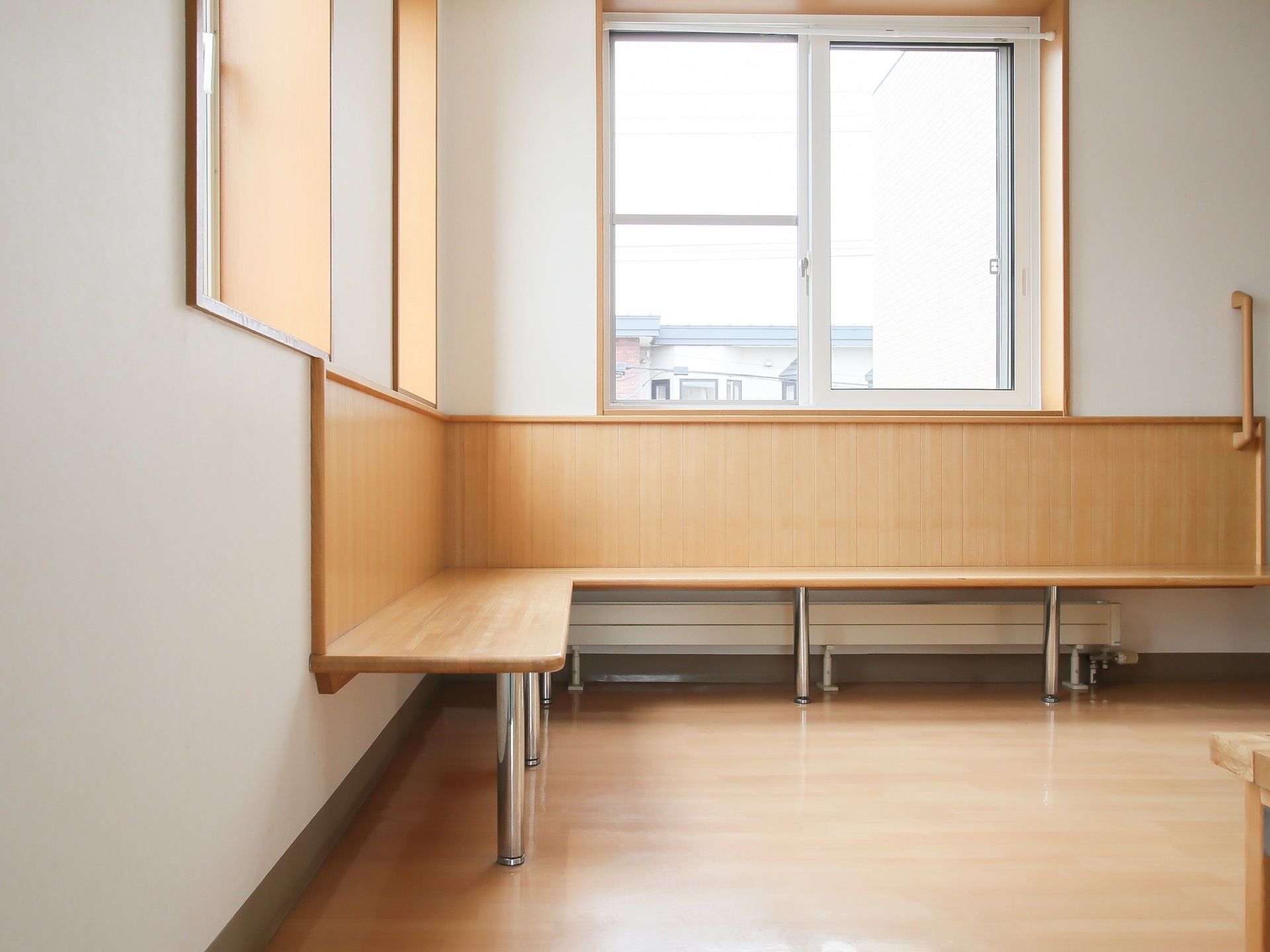 正面と左側に窓があり、その下の壁際に木材を使用したベンチが設置されている。壁に手すりが取り付けられている。