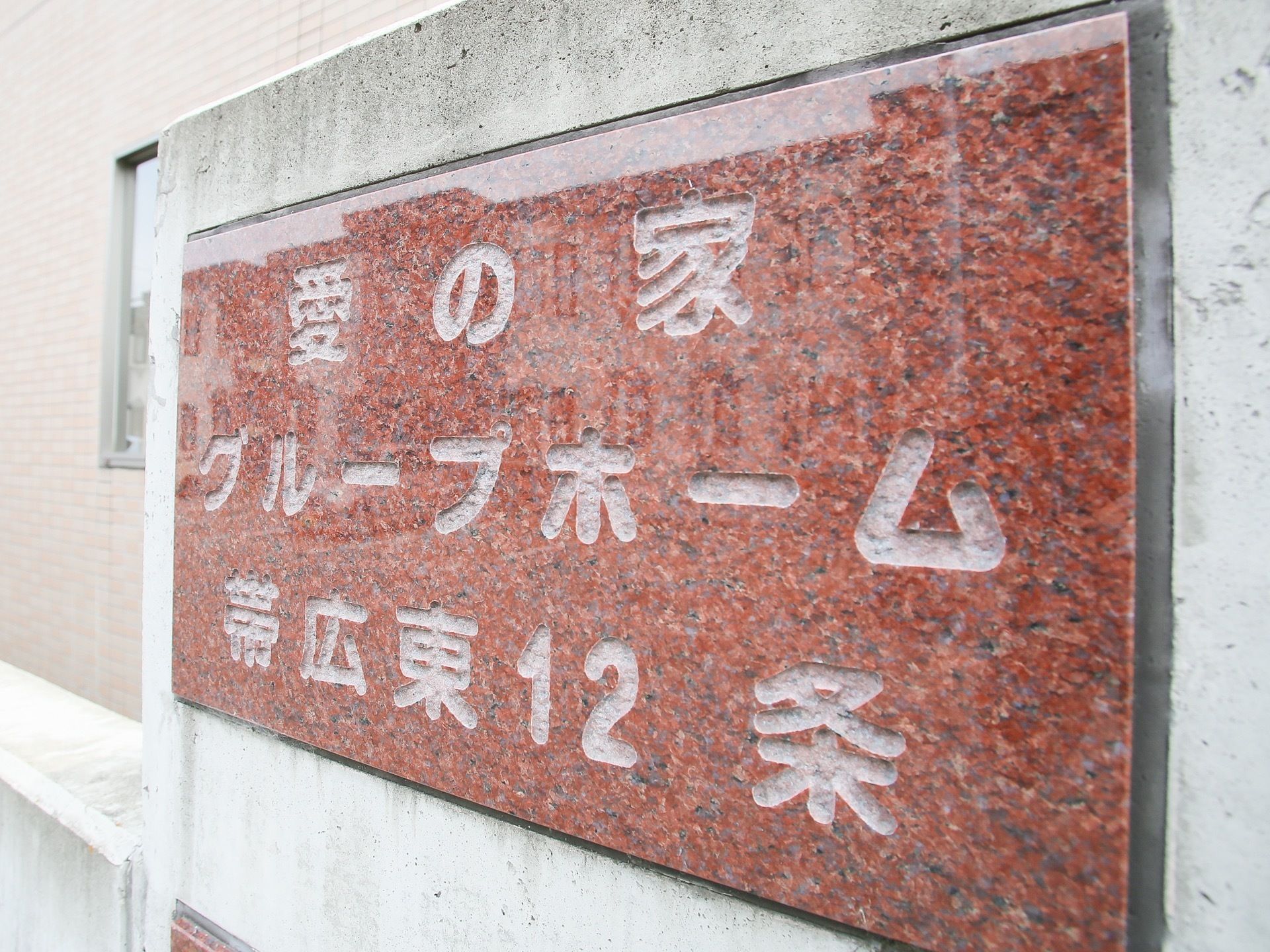 石材を利用した大きな看板が施設の外に取り付けられている。茶色い石に施設名が掘り出され、壁に埋め込まれている。
