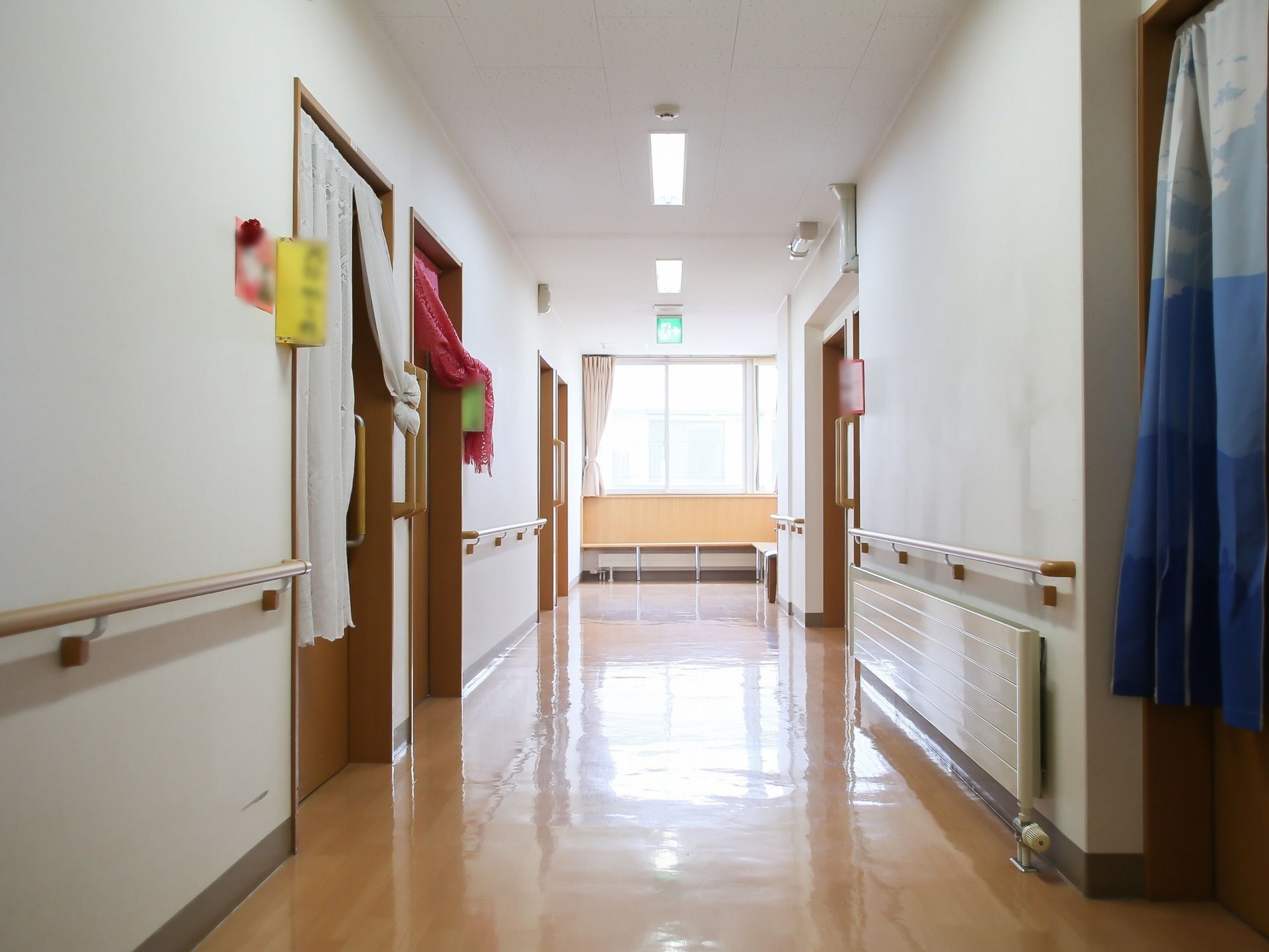 きれいに磨かれた廊下が真っ直ぐ伸びている。正面に大きな窓があり、壁に木製のベンチが作りつけられている。