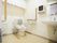 個室トイレの画像である。中央に洋式トイレがあり、温水洗浄便座や手すり、背もたれパッドが取り付けられている。