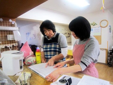 バインダーに留めた書類を使って打ち合わせをする二人の女性職員