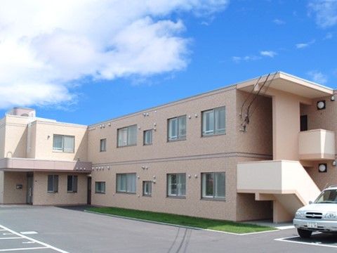 ホームは薄いピンク色の外壁の建物にある。建物の前には、アスファルトで舗装した広場があり、ラインを引いて駐車場を整備している。