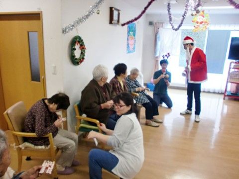 クリスマスにサンタやトナカイのコスプレをした職員とビンゴゲームをする利用者