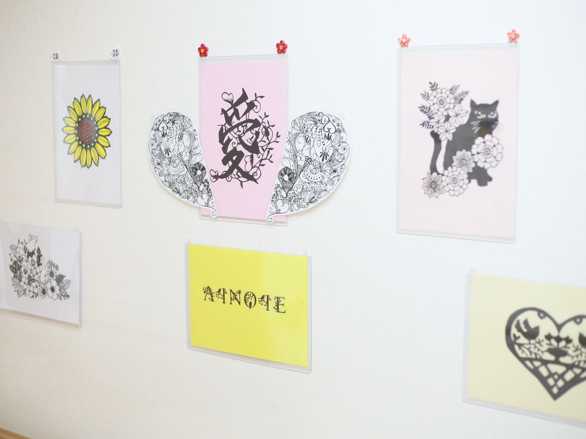 清潔感のある白い壁に、複数の作品が飾られている。花や猫などがモチーフにされており、繊細なタッチで描かれている。