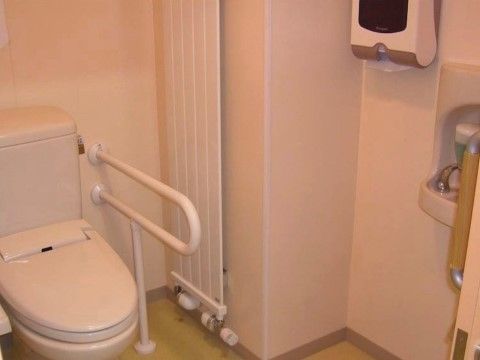 トイレのドアは高齢の入居者様にも扱いやすいスライド式で、取っ手を左右に動かして開閉する。個室内は空間に余裕を持たせている。