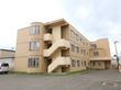 オレンジ色のタイル調の壁が特徴の建物である。非常階段横の出窓がオシャレである。建物の周りは駐車スペースとなっている。