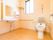 洗面台とトイレが一つの空間にある。洗面台の近くには窓があり、窓の下には手すりが取り付けられている。トイレの便器両側にはひじ掛けが付いている。