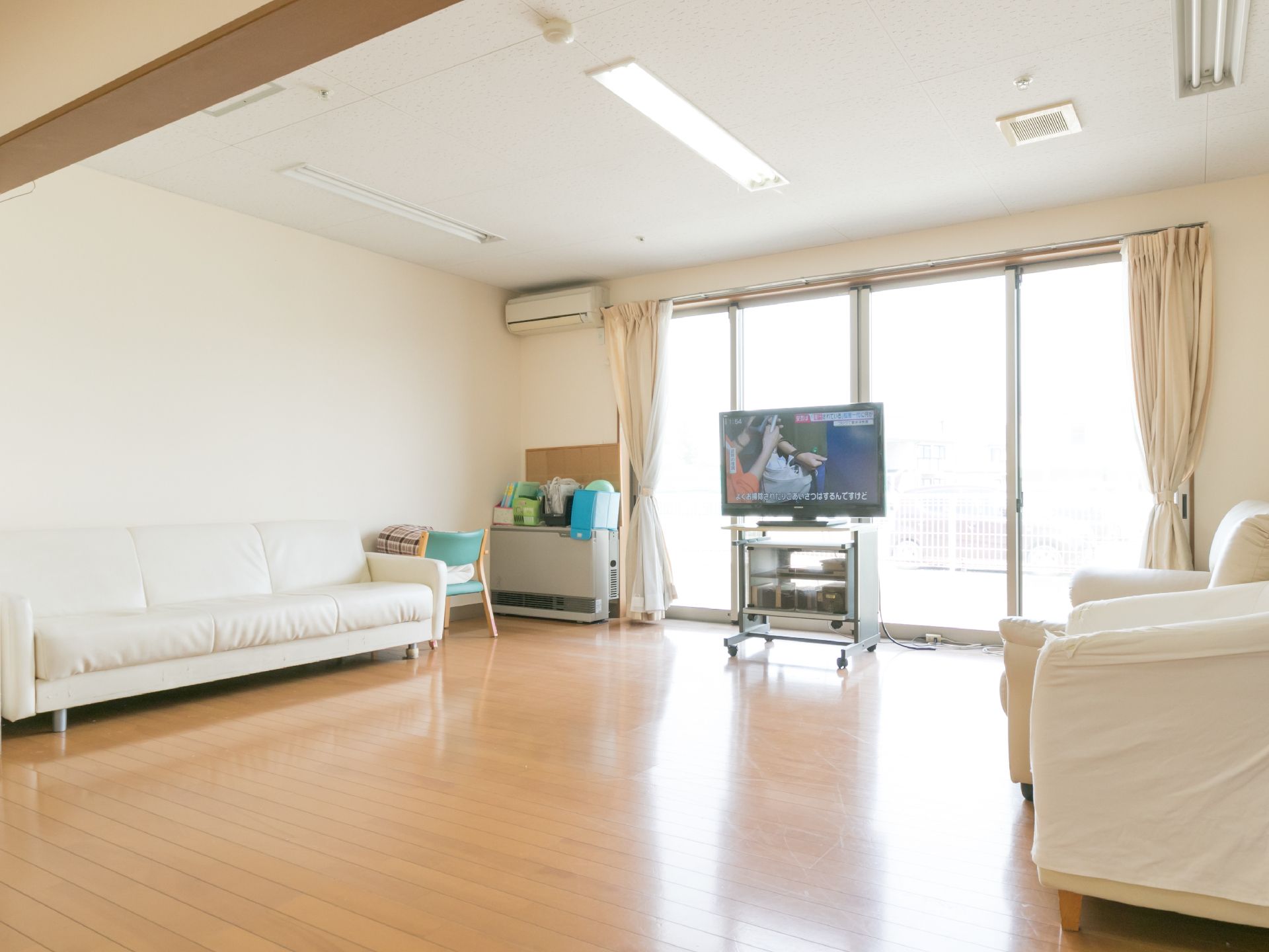 ナチュラル系の色のフローリングの共有スペースには、ソファーとテレビが設置されている。窓が大きく、光がたくさん入ってくる。