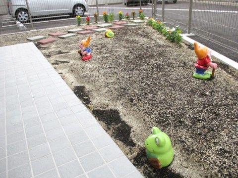 カラフルな鉢植えとカエルやドワーフの人形を置いた砂場