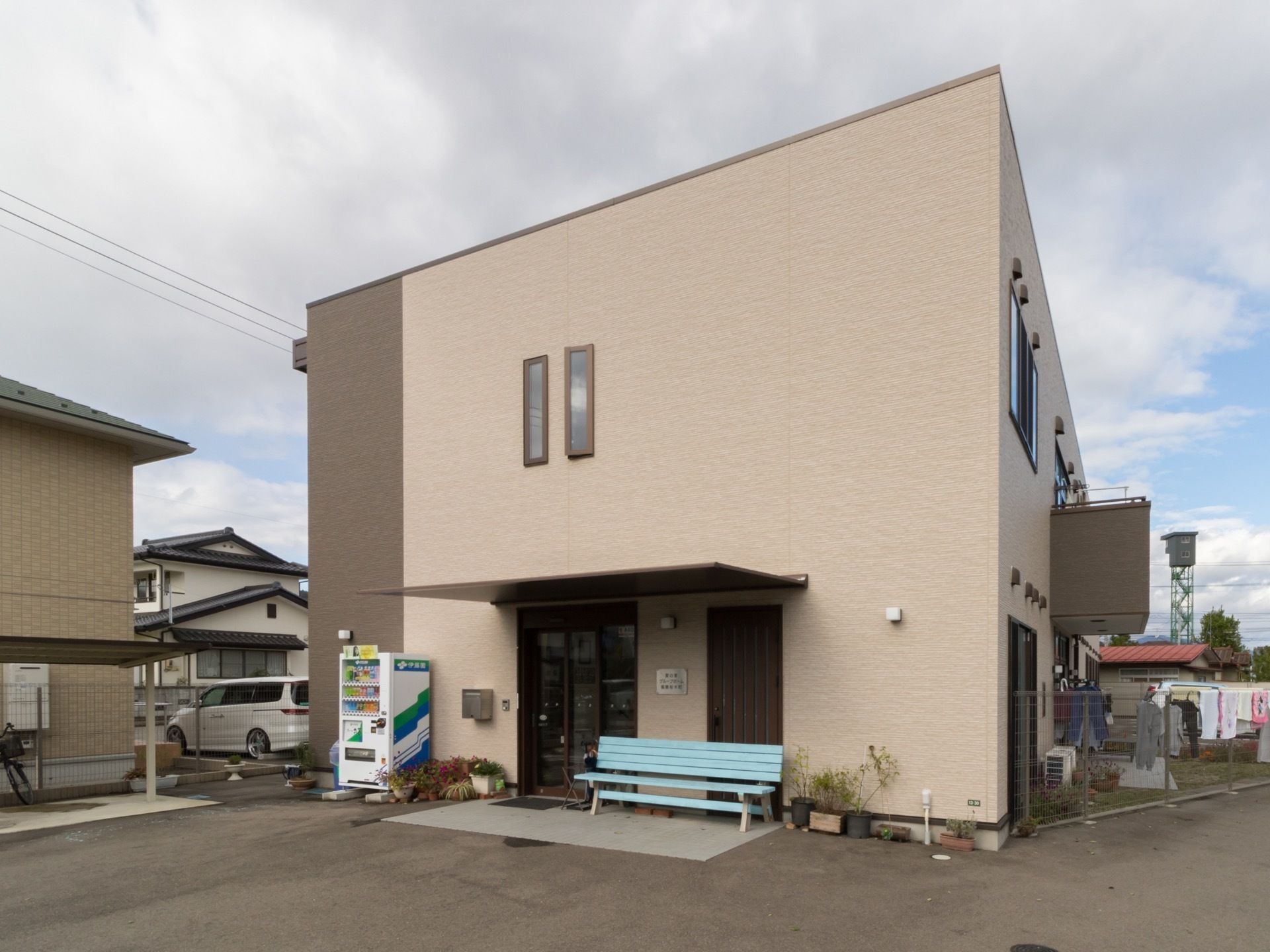 薄い茶色を基調とし、横側に焦げ茶色の縦ラインの外観の２階建ての施設である。玄関前には、水色のベンチを置いている。