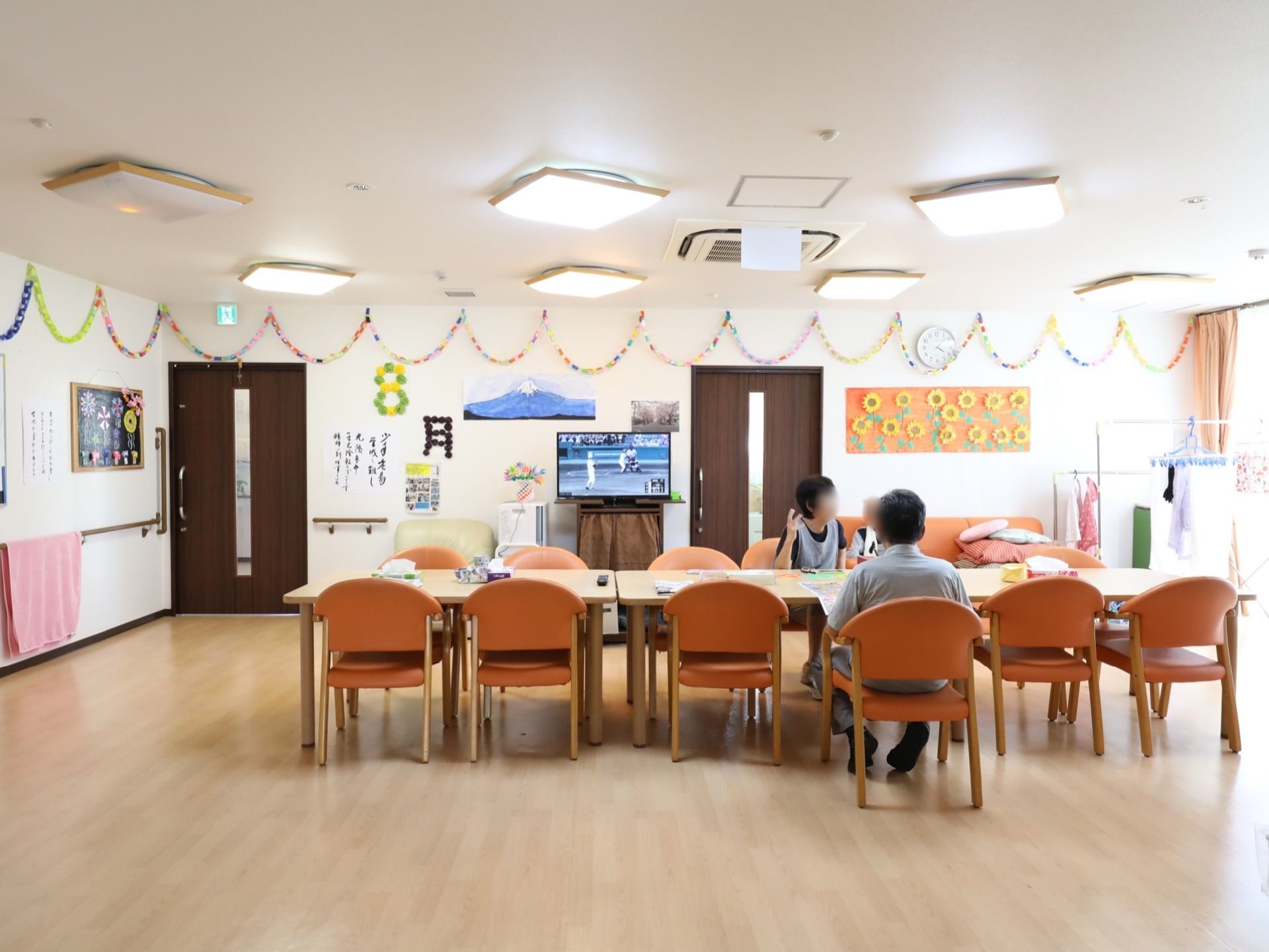 手作りの季節飾りが施されたリビング。テーブルや椅子が複数セッティングされており、天井には複数の照明が設置されている。