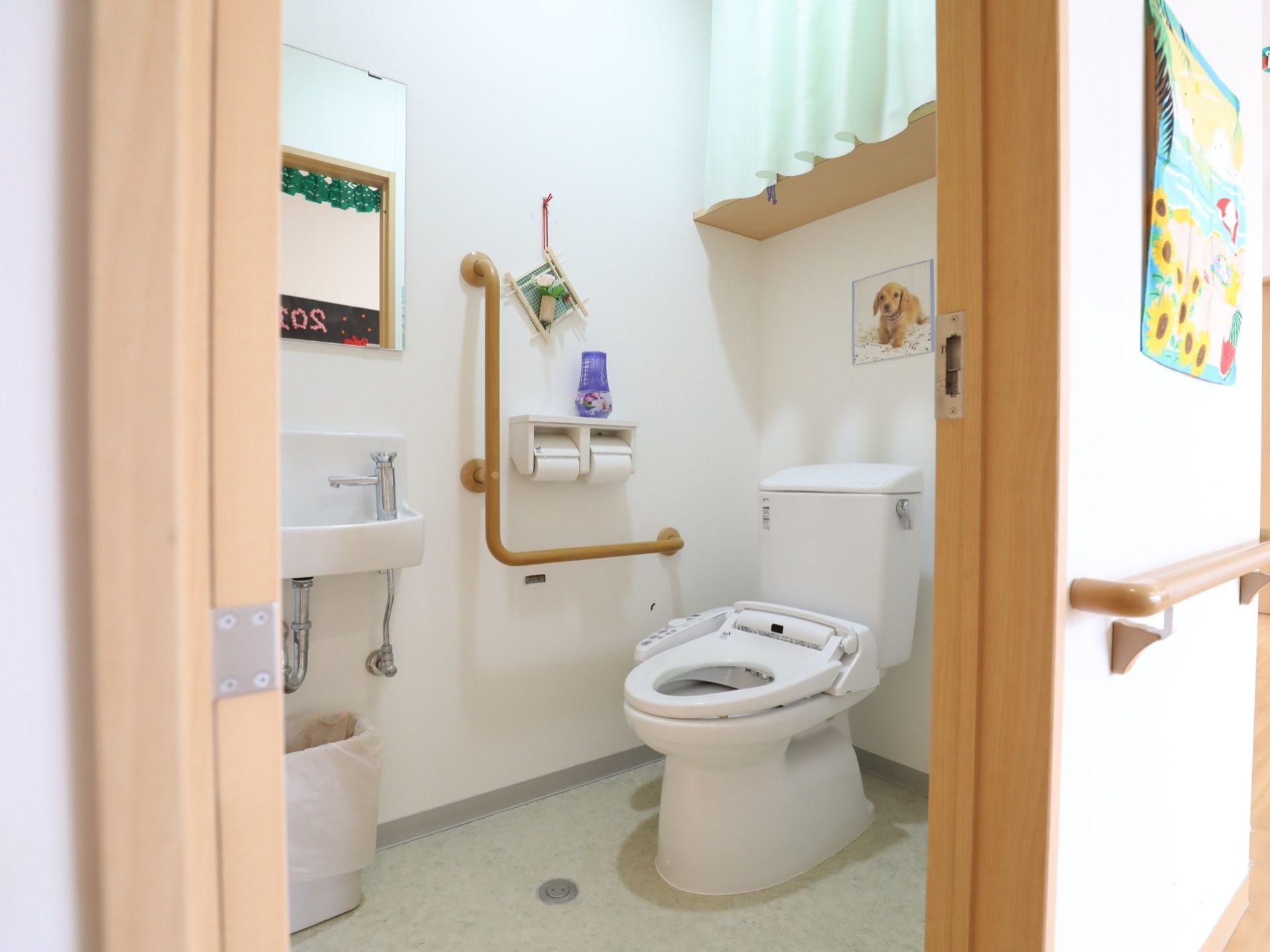 広いスペースが確保されているトイレである。温水洗浄便座器やＬ字型手すりが設置され、快適で安全に用をたすことができる。