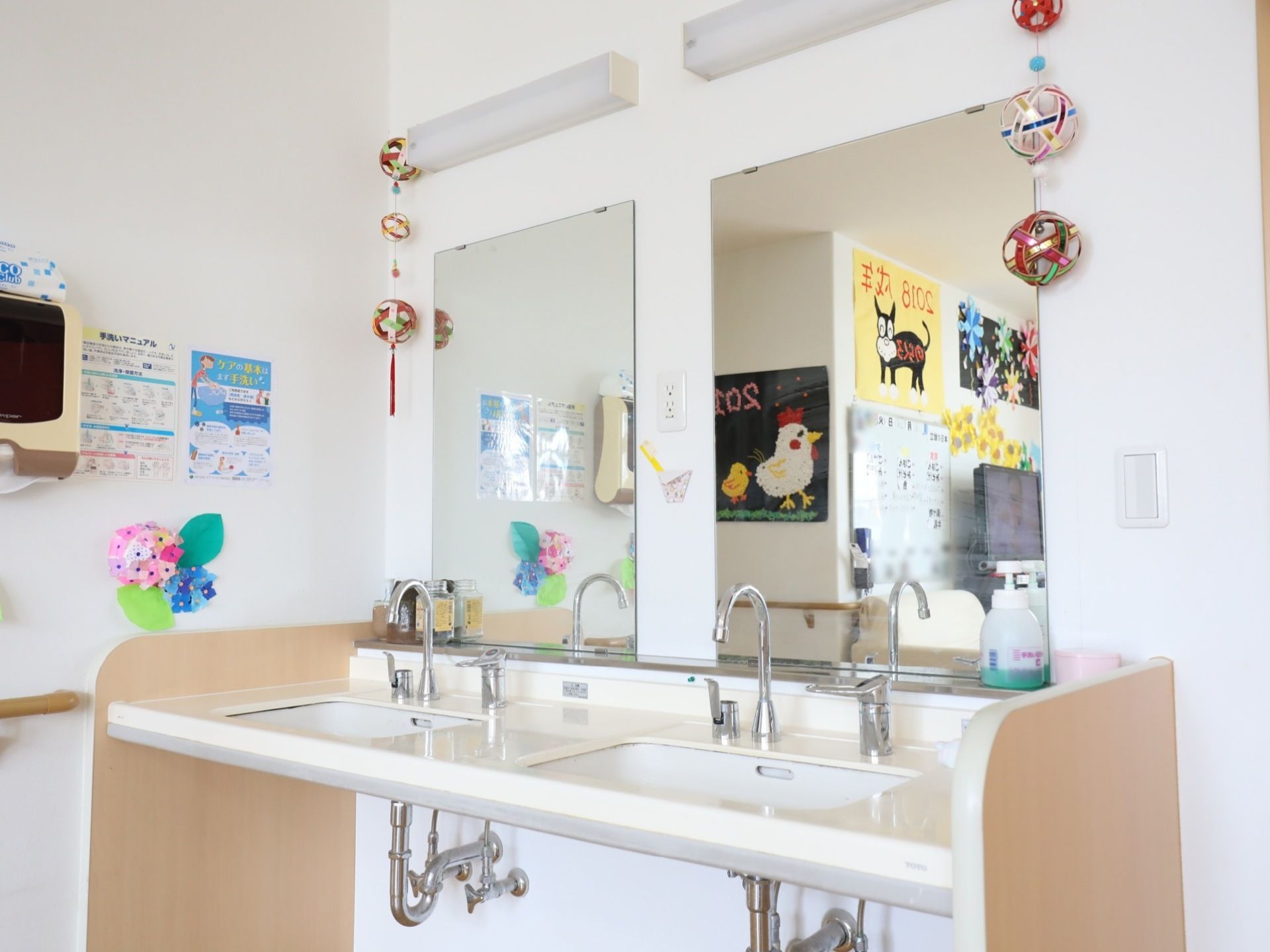 足元にゆとりあるスペースの洗面台が２面並んで完備されている。清潔にすっきり整えられており、壁には飾り付けがされている。