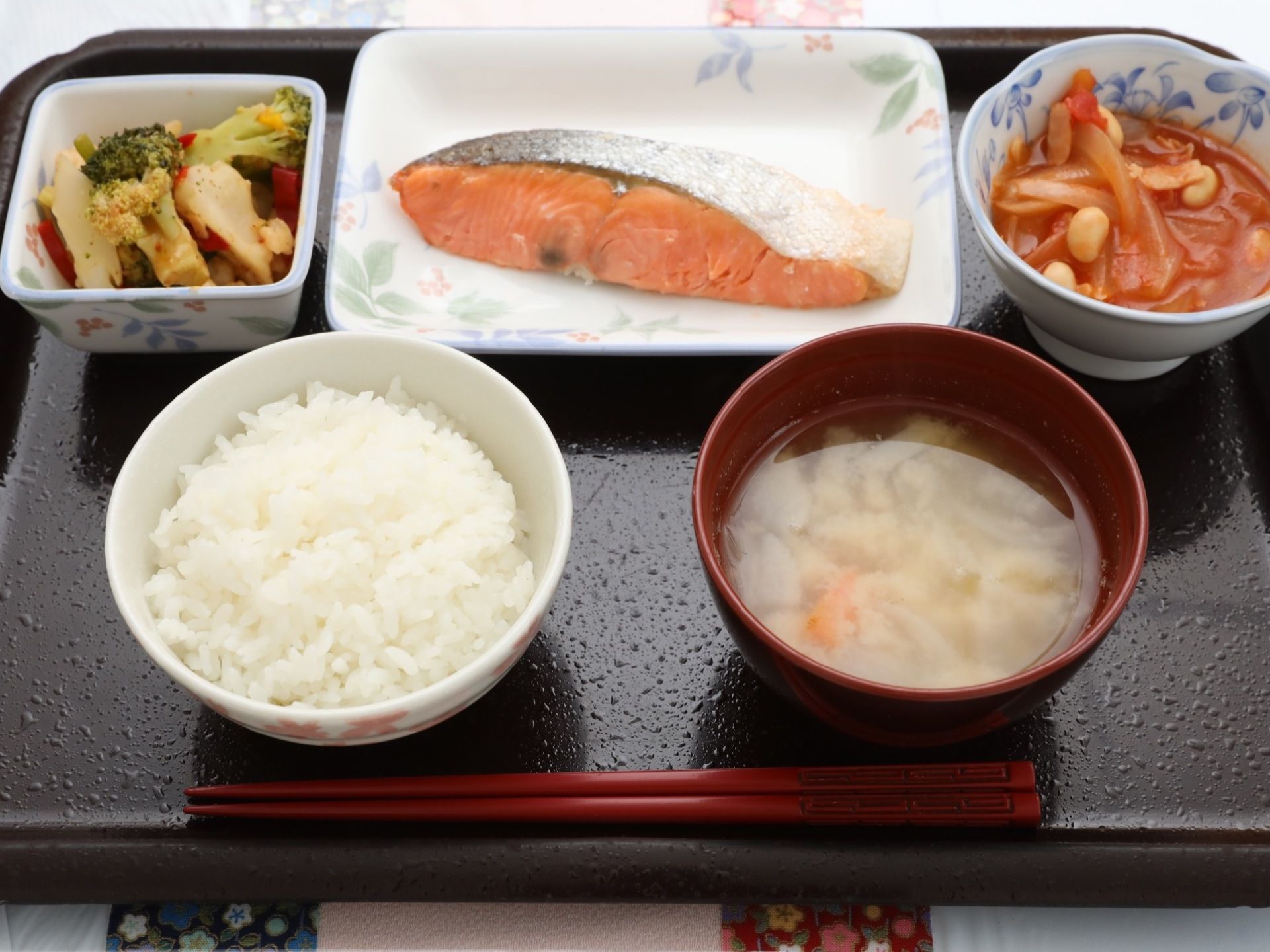 黒いプレートで配膳された食事の一例である。一汁三菜で栄養バランスが整えられ、器や盛り付けにも配慮されている。