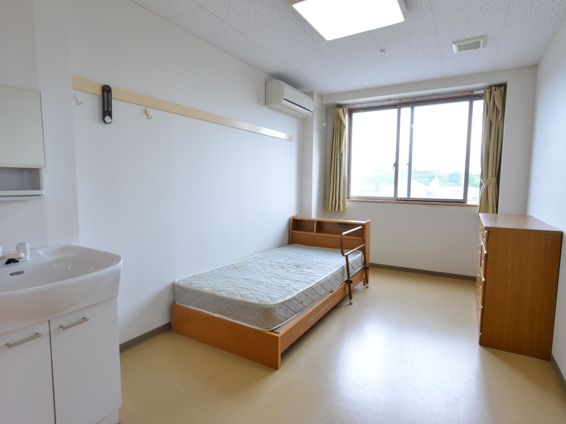 居室は洋室。枕元に収納スペースがあるベッドが設置されている。壁には物を掛けられるフックがついている。