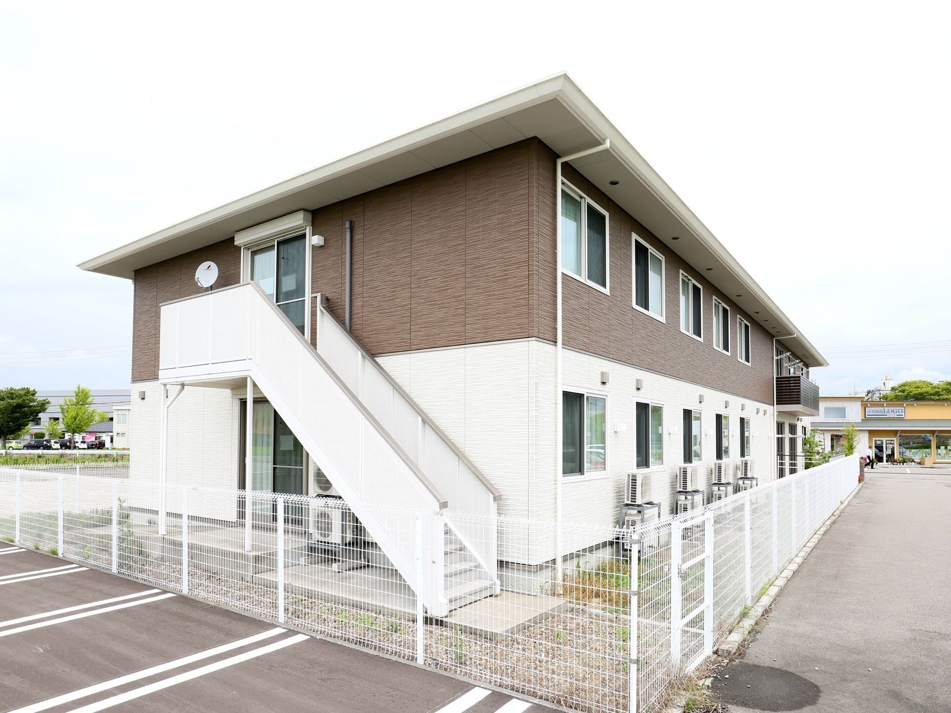 白と茶の外壁で施された、２階建ての施設である。まわりに白色のフェンスが設置されている。敷地はアスファルト。