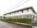 建物全体が２色に塗り分けられた施設で、１階がグレー、２階がベージュに塗られている。右側の壁に外階段がある。