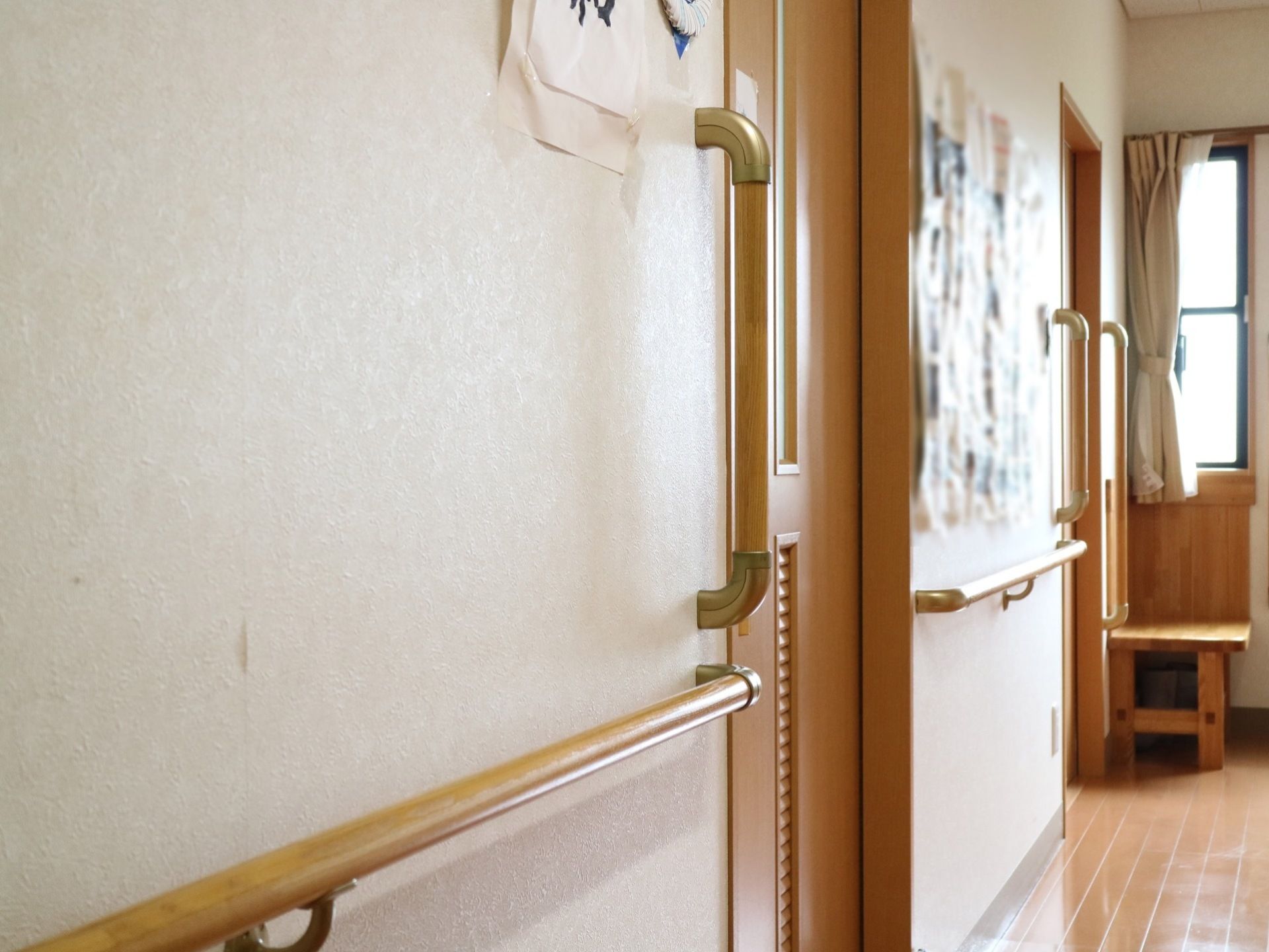 居室の出入り口や壁に、手すりが備え付けられている。床はフローリングタイプである。窓から自然光が降りそそいでいる。