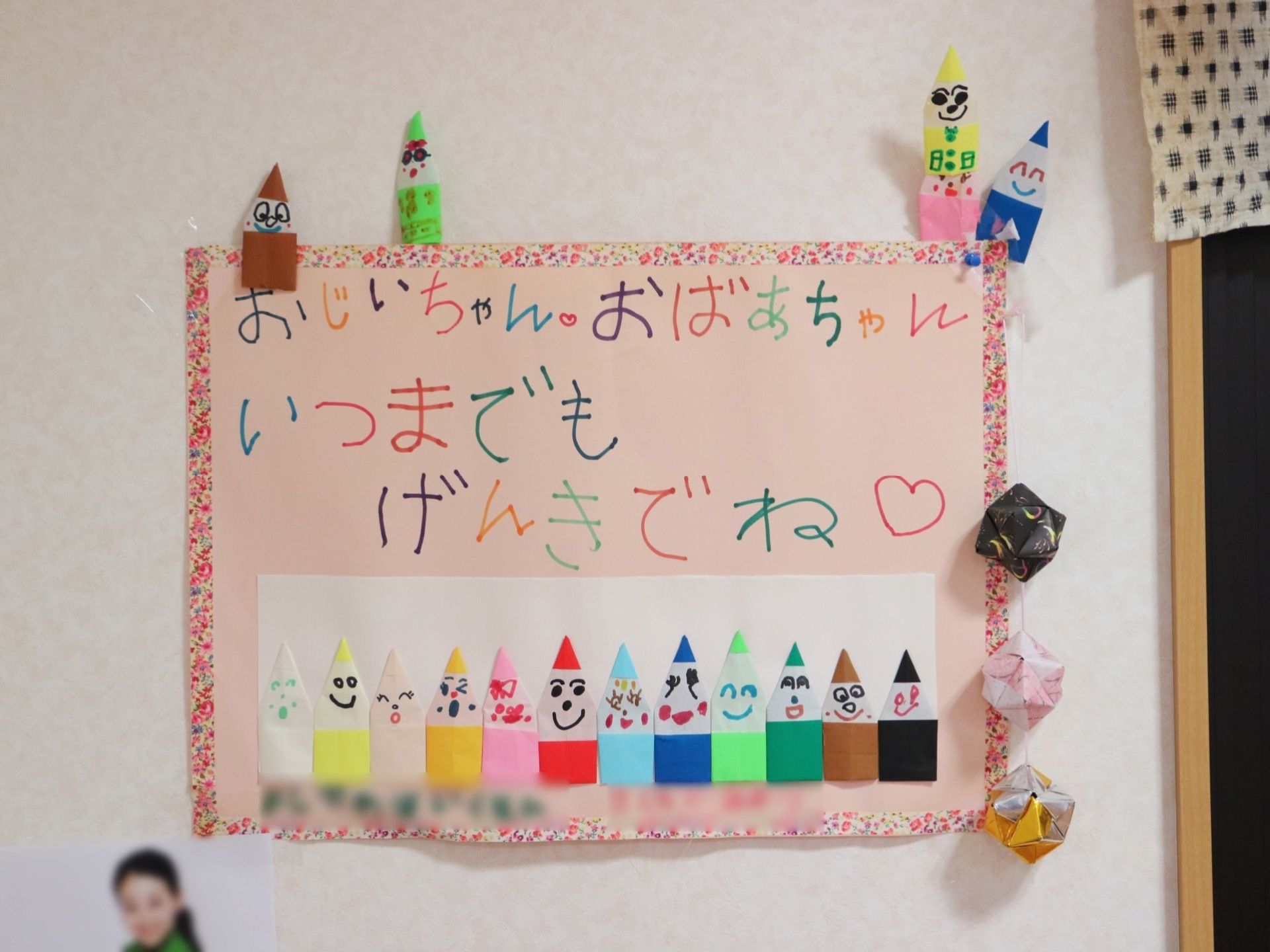 シンプルな白色の壁に、子どもが制作した作品が飾られてある。いろいろなカラーを使い、文字やイラストが描かれている。