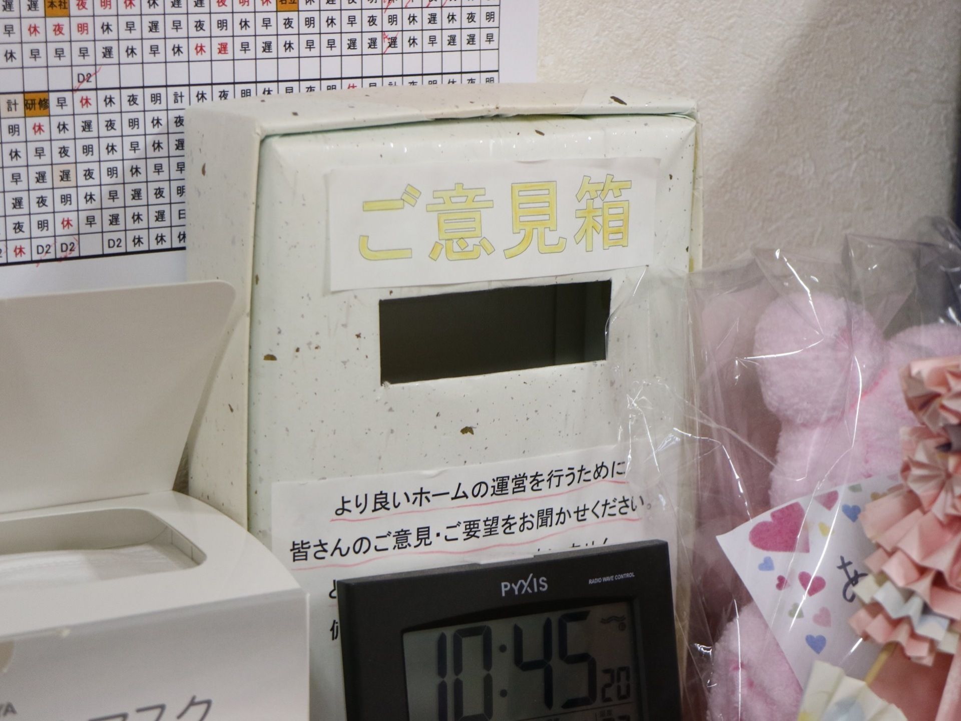館内にご意見箱が設置されている。ぬいぐるみやデジタル時計が置かれてある。壁には、シフト表が貼られている。