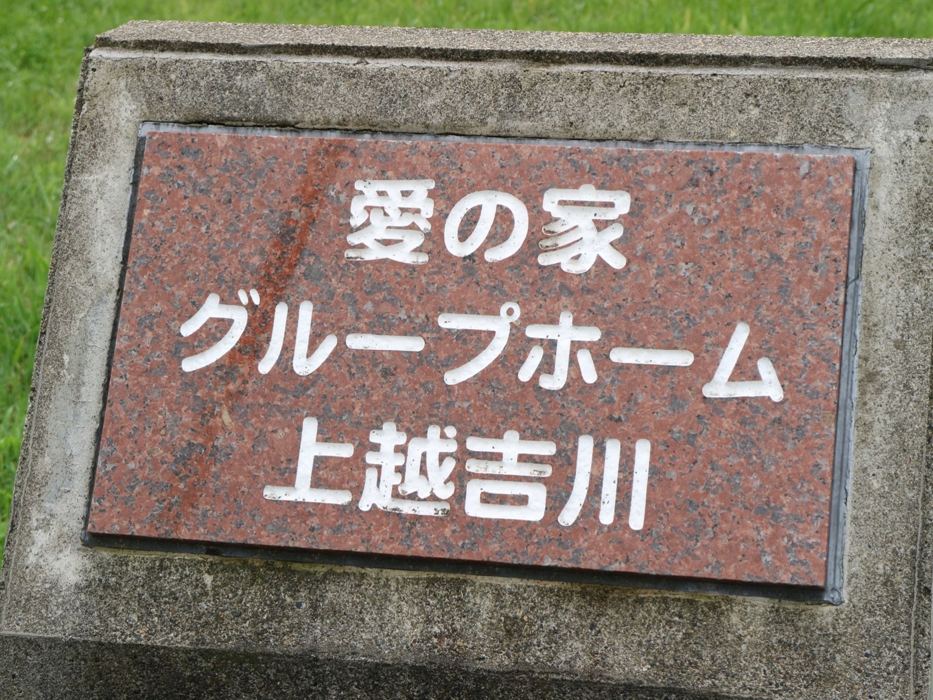 豊かな緑に囲まれた施設である。コンクリートのブロック塀に、看板が設置されている。大きな文字で記されてある。