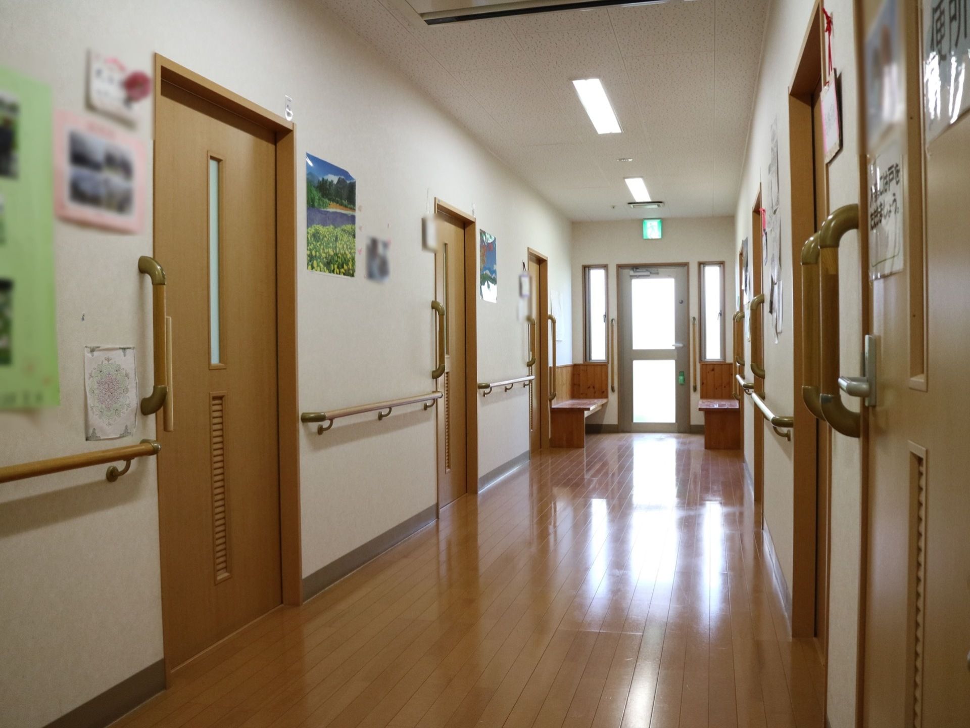 廊下は幅が広く、車椅子をご利用の方でも移動しやすい。居室へのドアは茶色で、スライドタイプとなっている。