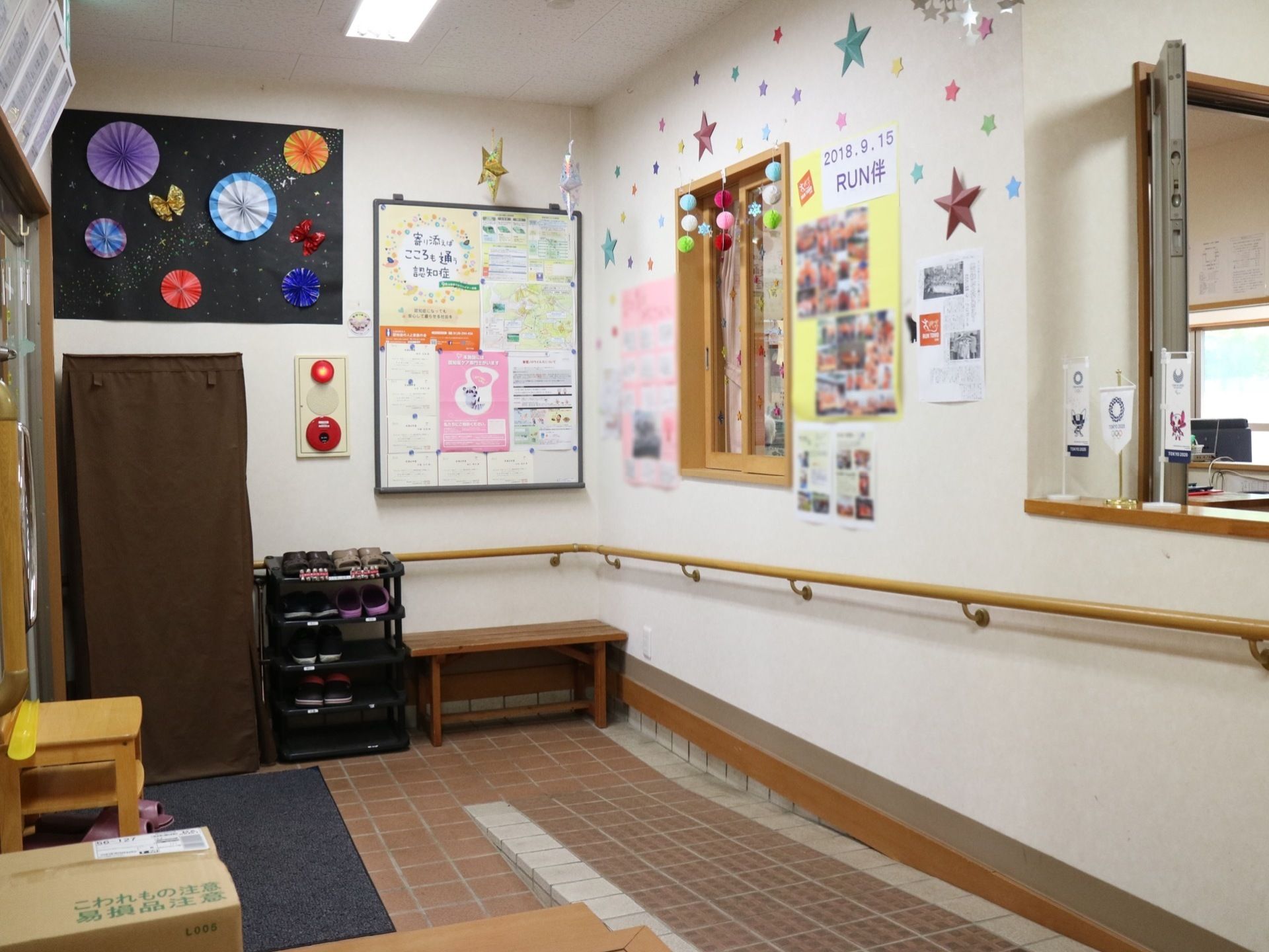 玄関にはスリッパラックや、小さな茶色いベンチがある。なだらかなスロープが設置され、壁に沿って手すりも付いている。