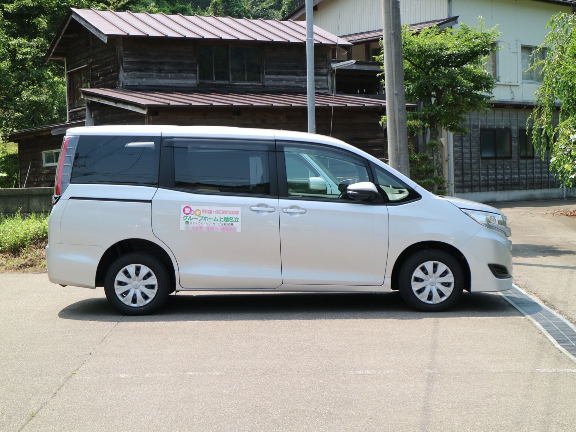 施設には駐車スペースがある。薄く白線が敷かれている。施設用の白い車が駐車してある。ドアには施設名が表示されている。