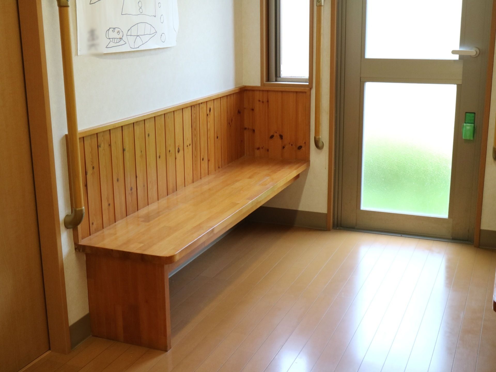 入口ドア付近には木製のベンチがある。ベンチは横に長く、数人が座れるほどの大きさである。壁側に縦長の手すりが付いている。