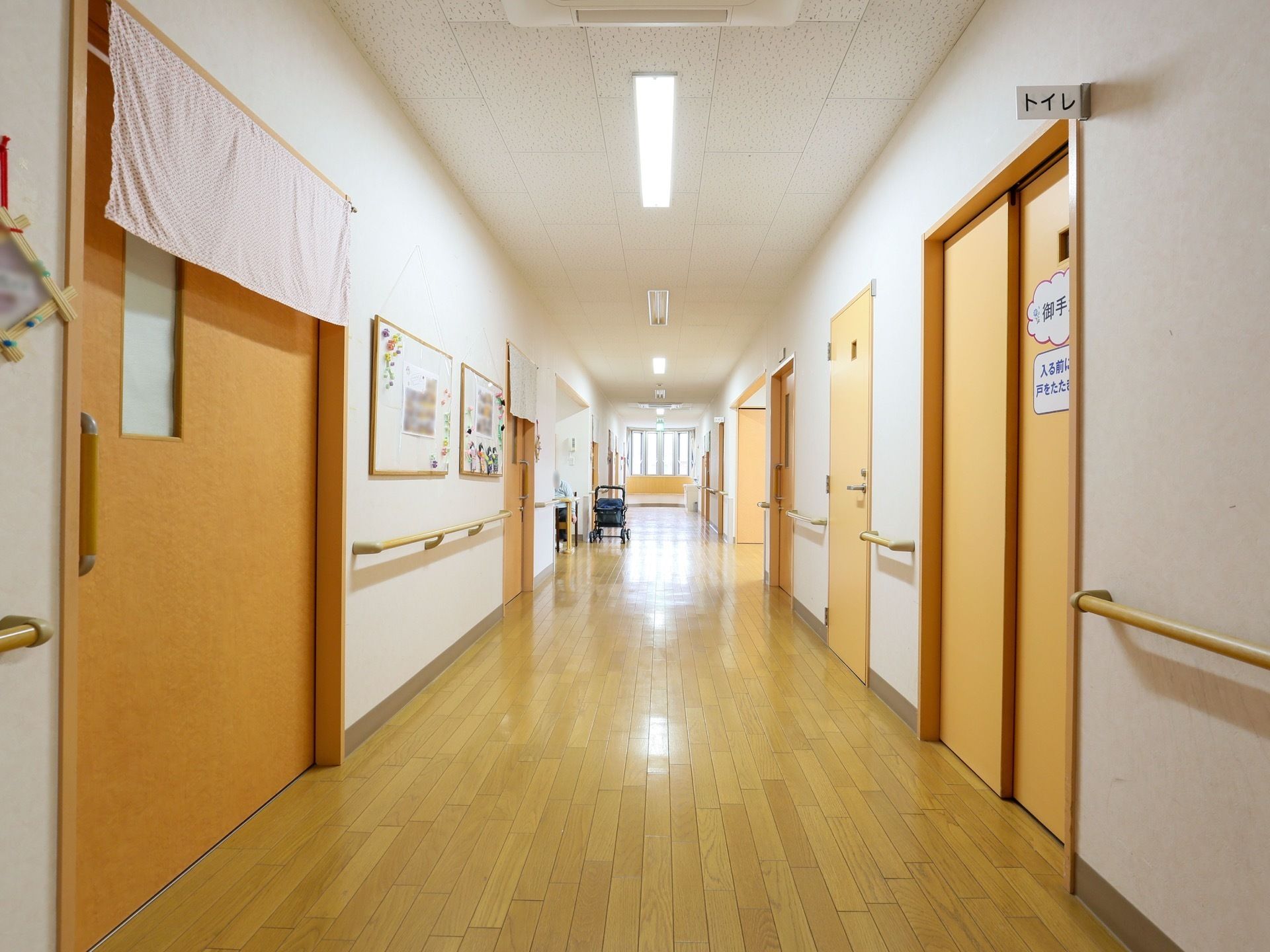 木の質感を大事にした明るく広い廊下は、入居者様の利便性に配慮している。手すりも多いので、足元が不安な方にも安心な設計になっている。
