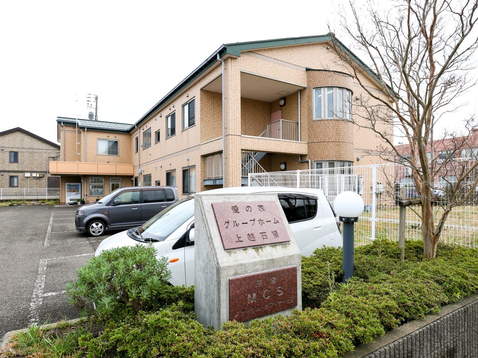 別の角度から見た外観と駐車場。静かな環境がよく分かる。専用の駐車場はスペースも広く、多くの来訪者様をお迎えできる。