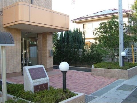 集合住宅のような建物の入口は段差のない設計になっている。看板のある植栽には照明があり、夜間でも明るい。