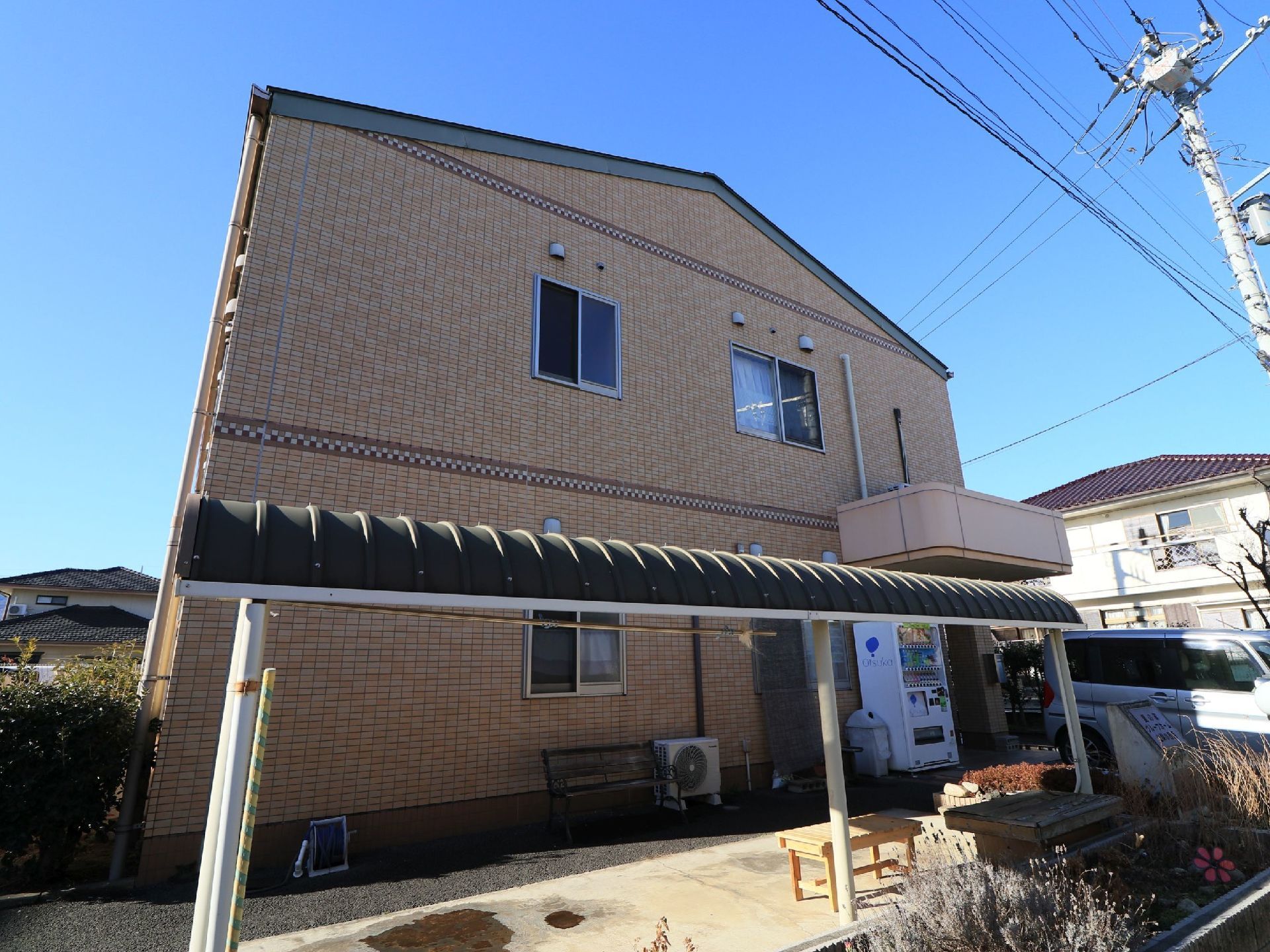 外壁はブラウンを基調としたタイル張りで、２階建ての建物である。建物の前方に屋根が設けられていて、その下にベンチが置かれている。