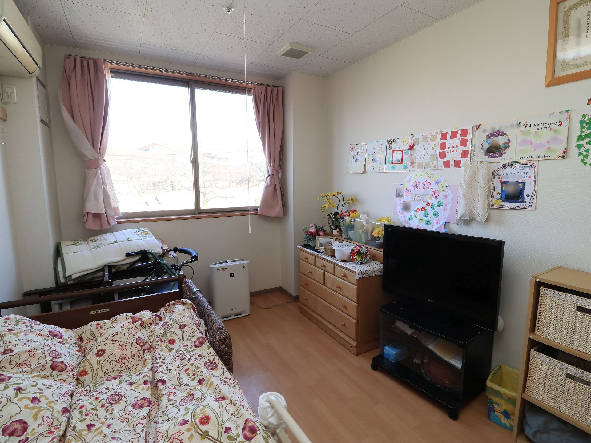 居室にはベッドやタンス、テレビなどが設置されている。タンスの上には鉢植えの花などが綺麗に並べられている。