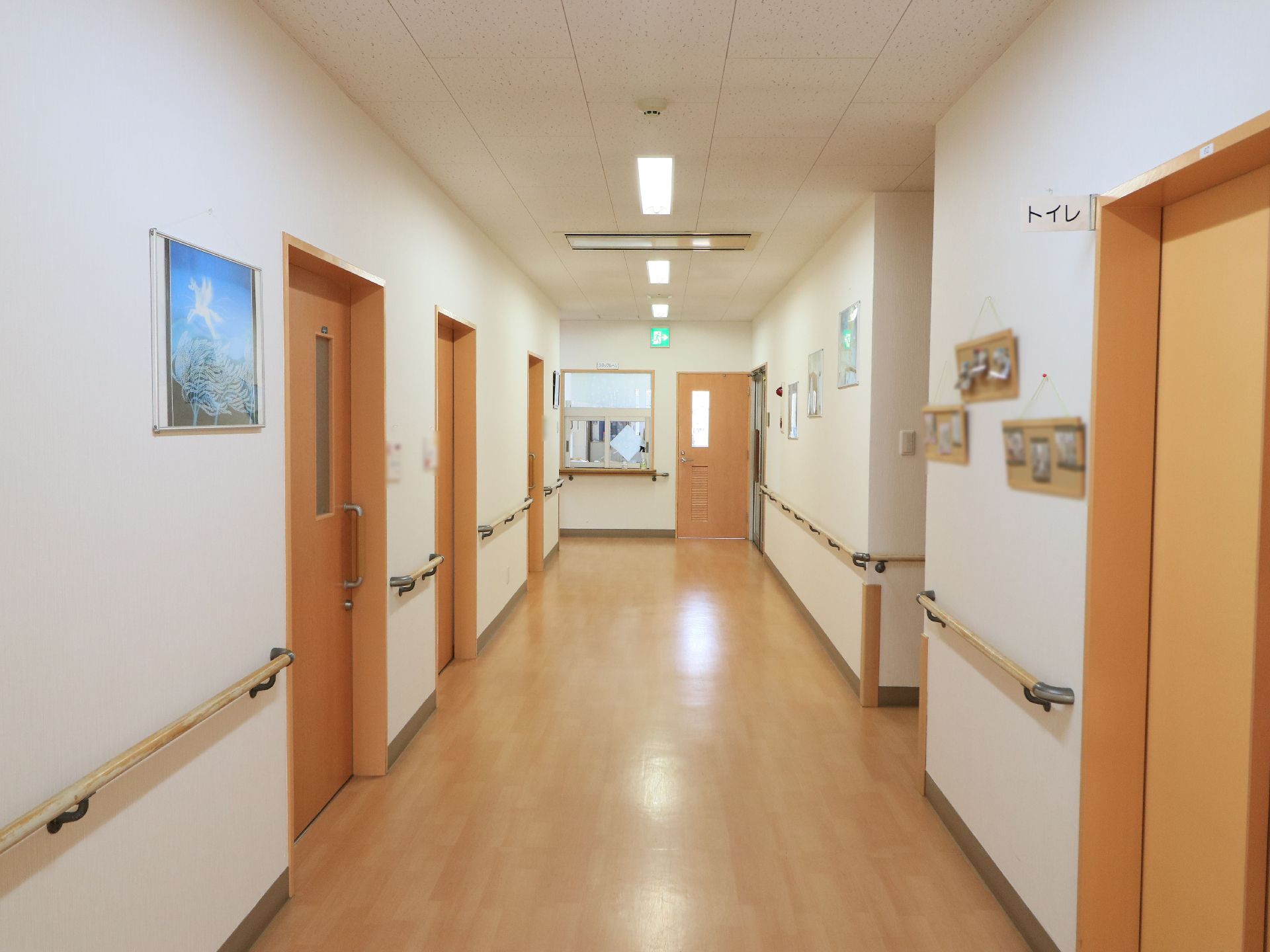 広々とした通路はフローリング張りで、隅々まで清掃が行き届いている様子である。両側の壁に手すりが取りつけられている。
