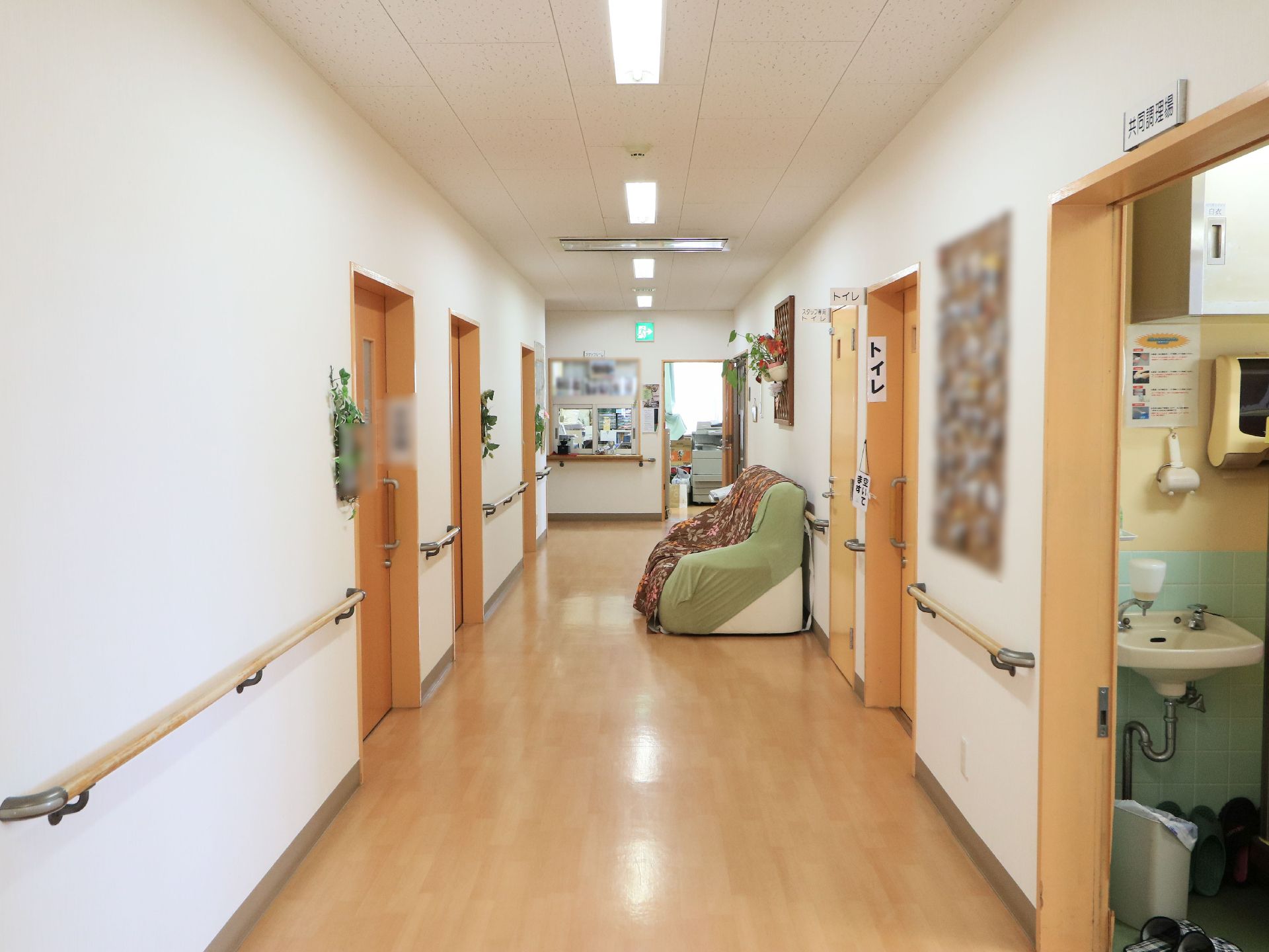 通路の途中にグリーンのカバーのかかったソファが設置されている。ソファの手前にはトイレと書かれた表示がある。
