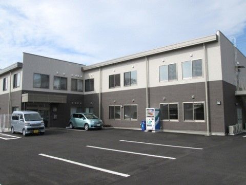 白とグレーの２階建ての施設である。敷地内には駐車スペースを設けている。駐車場は平らに舗装されているので、車椅子をご利用の方も移動がしやすい。