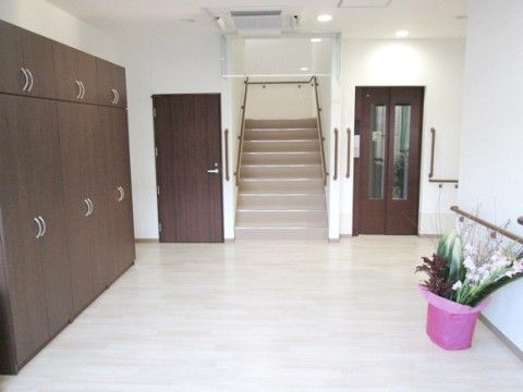 モノトーンのシンプルな内装に、大きな鉢花が華を添えている。エントランスは大きく開いており、階段や廊下へ続く道がはっきり見えてわかりやすい。