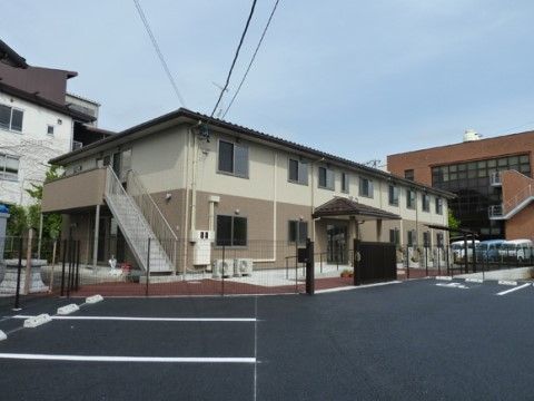 落ち着いた色合いの外装の２階建ての建物である。施設と駐車場はフェンスで区切られているので、安全に移動ができる。