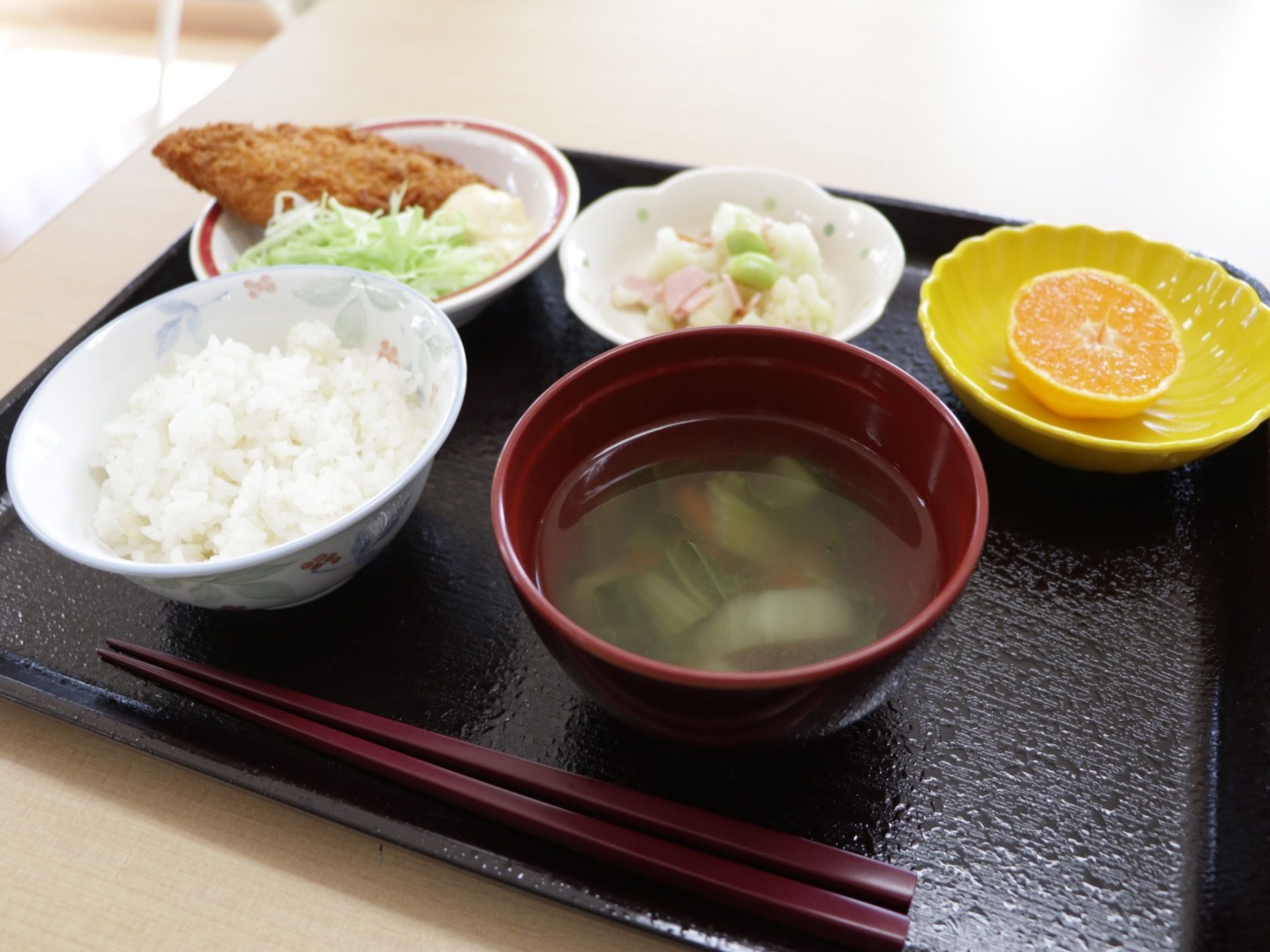フルーツもついたバランスのとれたメニューの食事がお盆に載せられている。食器はカラフルな陶器製のものが用いられている。