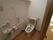 背当てのついた洋式便座がある個室トイレで、壁にＬ字型の白い手すりが設置されている。手すりの下にペーパーホルダーが備えつけられている。