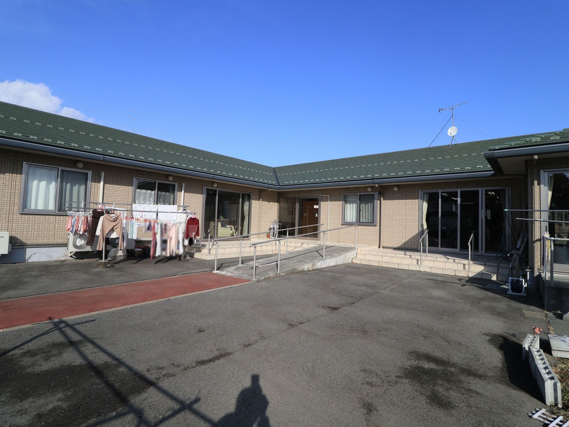 落ち着いた平屋造りの施設となっている。建物の前には、快適に車の出し入れができる広い駐車スペースが設けられている。