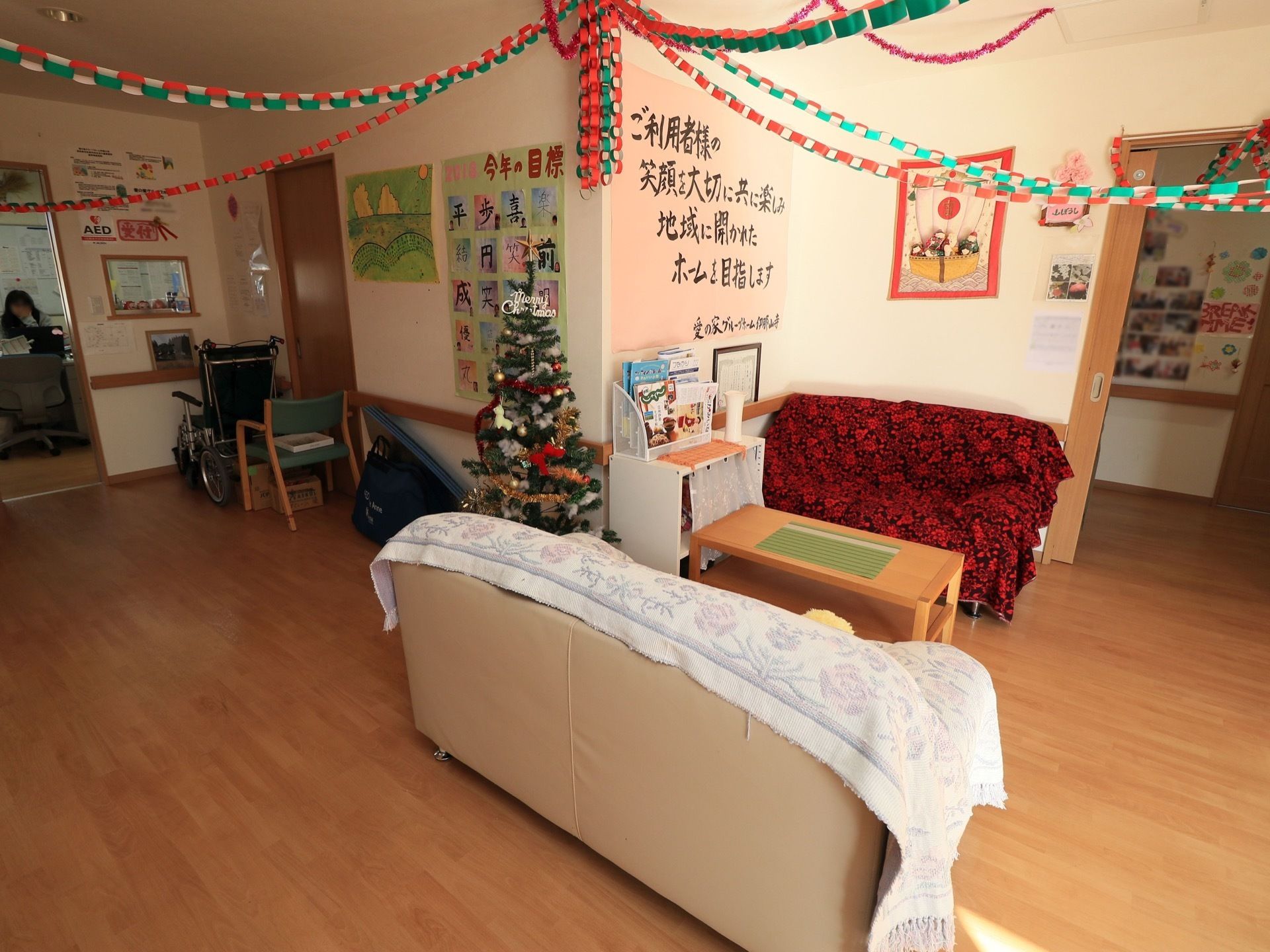 広い一室にクリスマスツリーが置かれている。壁や天井に手作りの装飾物が飾らており、華やかな雰囲気が演出されている。