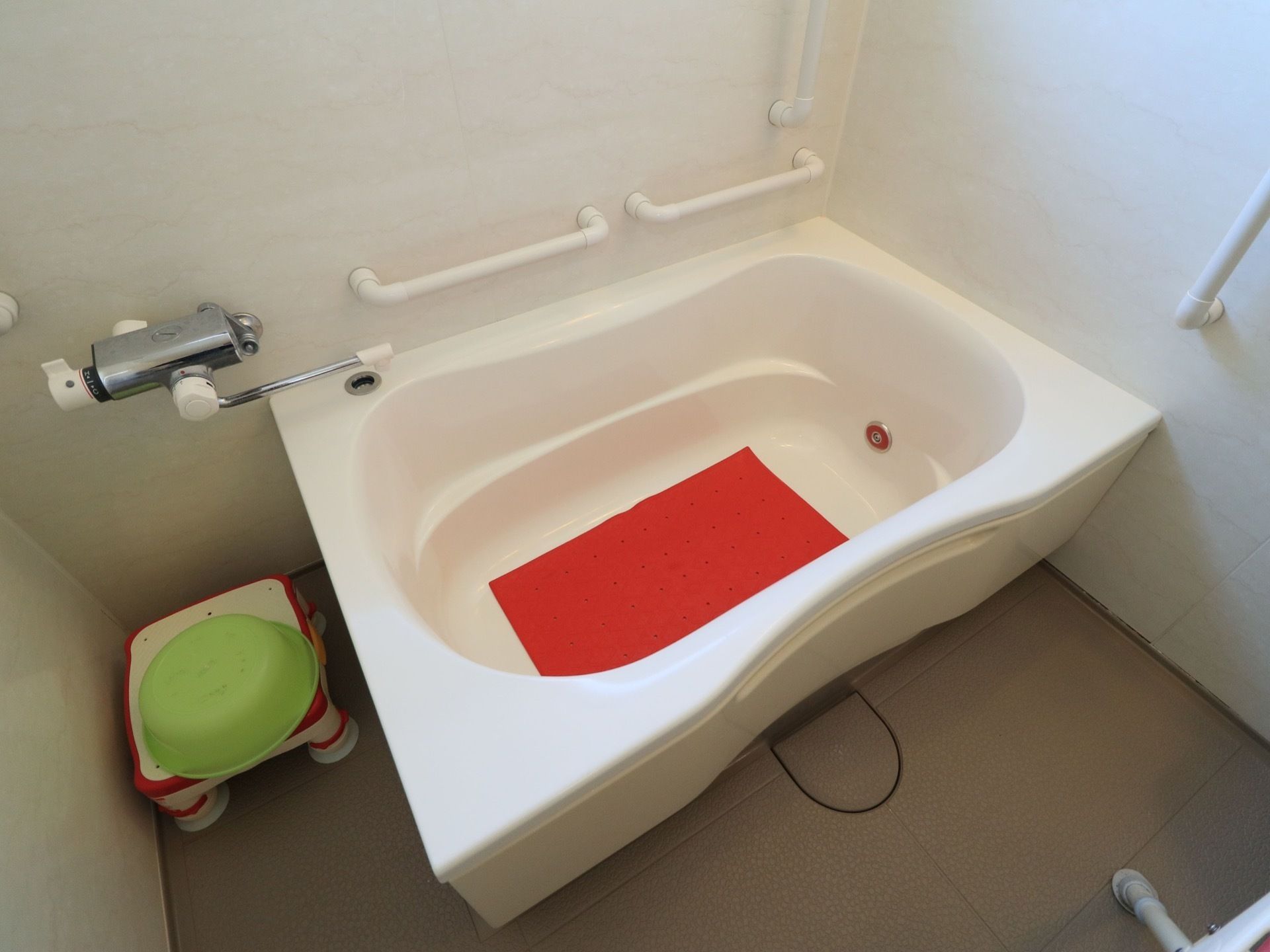 浴室の壁に手すりが設置されており、床にも滑りにくい素材が使用されている。浴槽の中には滑り止め防止のシートが敷かれている。