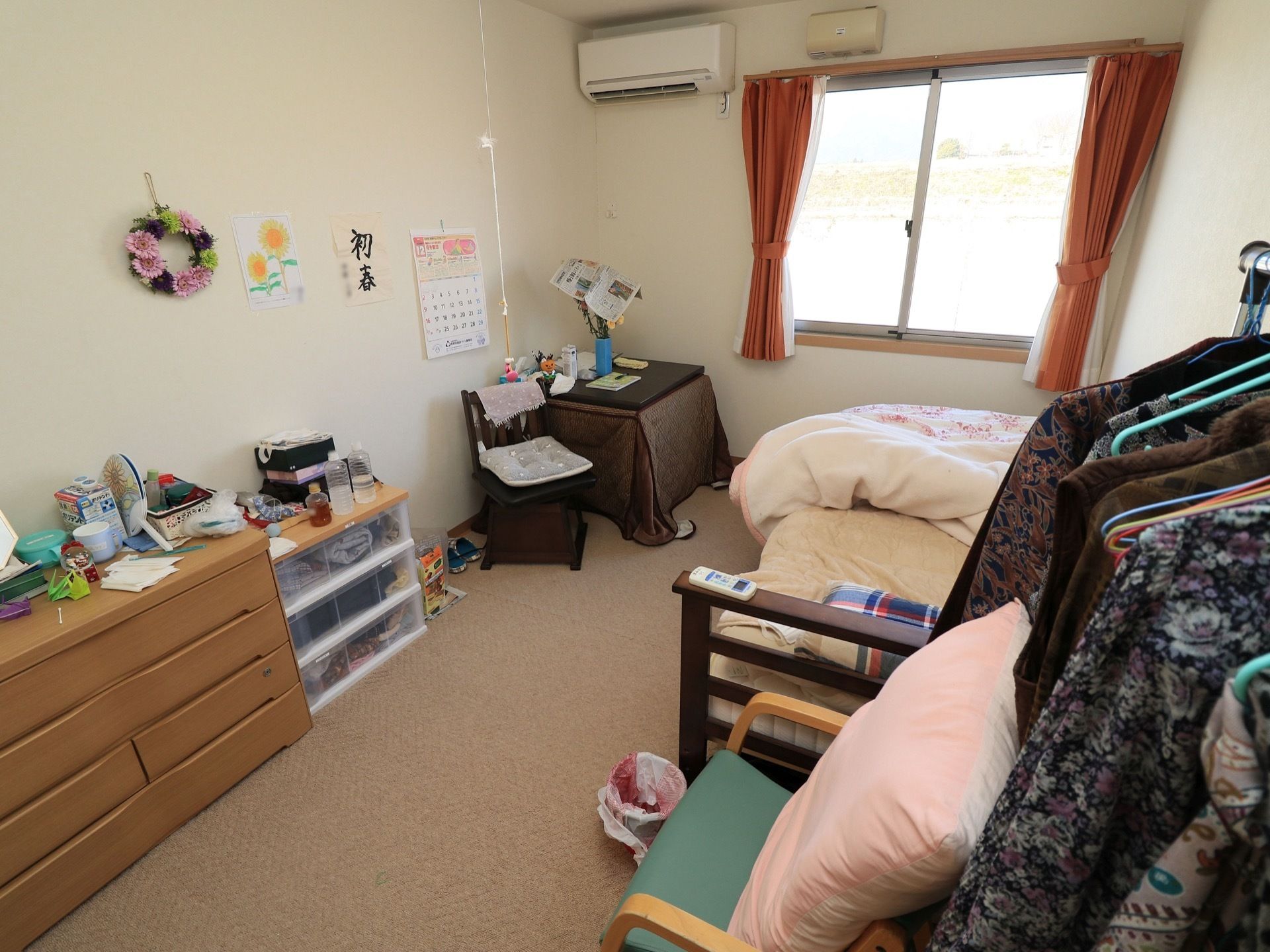 介護用ベッドや収納棚が置かれており、ハンガーにはたくさんの服が掛っている。壁には絵画や装飾物が飾られ、華やかな一室になっている。